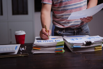 A man sits at his desk at home at night, working on his laptop. He views charts, checks documents, and analyzes financial data, focusing on investments, stock trading, and shareholder rights