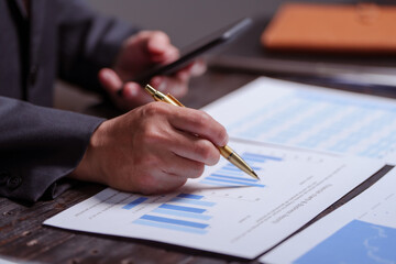 Naklejka premium A man sits at his desk at home at night, working on his laptop. He views charts, checks documents, and analyzes financial data, focusing on investments, stock trading, and shareholder rights