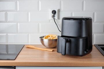 Trendy kitchen gadget air fryer machine cooking deep-fried potato. Lifestyle of new cooking, small...