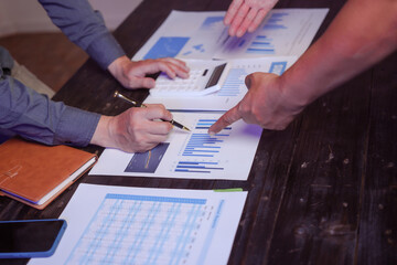 A close-up of a male businessman at his desk, analyzing overtime graphs and business charts in a...