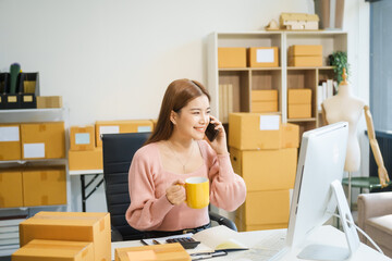 An Asian businesswoman sits at her desk, working on online sales and e-commerce marketing...