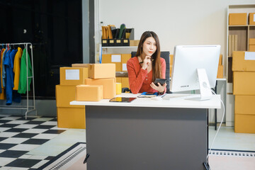 An Asian businesswoman sits at her desk, working on online sales and e-commerce marketing...