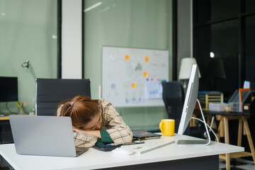 A businesswoman working at a desk in an office struggles with stress and headaches caused by Office...