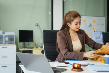 A young female lawyer sits at her desk in the office, providing online legal advice professionally....