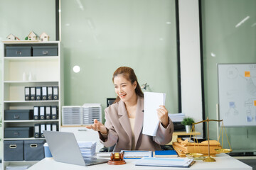 A young female lawyer sits at her desk in the office, providing online legal advice professionally....