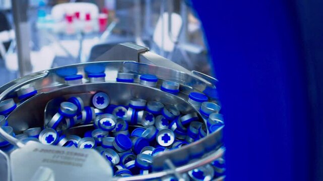 Pharmaceutical vial cap mixing equipment. A lot of aluminum vial caps are moving along the production line. Modern pharmaceutical equipment. Close-up