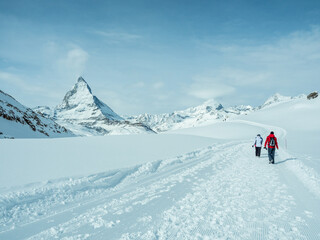 Hikers exploring snowy landscape in Zermatt, Switzerland with Matterhorn mountain view
