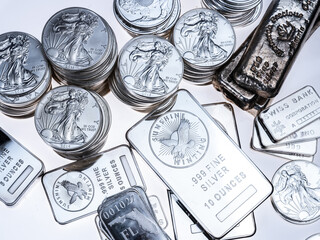 Overhead view of silver coins and bars on white background 