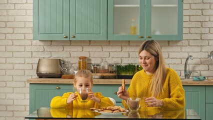 Mother and daughter together in the kitchen, mom teaching girl how to make gingerbread cookies, mom...