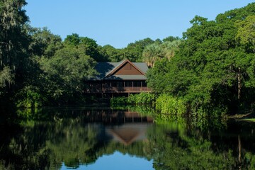 Fototapeta premium A serene lake house with a wooden deck, reflecting on the calm waters under a clear blue sky