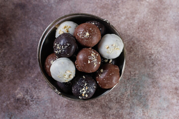 Homemade chocolate truffles with dark chocolate ganache covered with pink powder, waffle crumbles, gold flakes, coconut and nuts