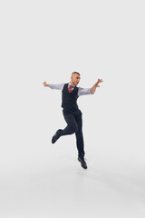Man in formal attire leaps mid-air with arms extended outward and energetic expression, wearing polished black shoes against white studio background. Concept of professional development, movement. Ad