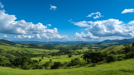 Obraz premium Stunning Panoramic View of Lush Green Valleys Under a Bright Blue Sky with Fluffy White Clouds in a Serene Natural Landscape