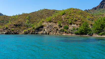 Fototapeta premium Aquarium bay in Aegean Sea with blue, turquoise and green water. Turkish islands, Boat trips along Aegean islands in Turkey to swim or snorkel