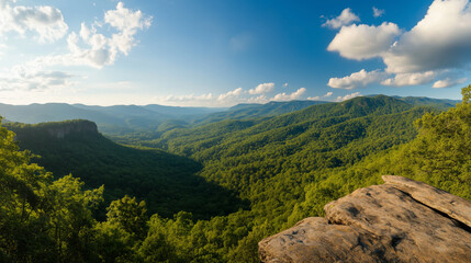 Obraz premium Lush mountain landscape under a bright blue sky in summer with fluffy clouds and distant hills