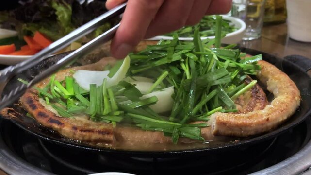 잘 익은 한국식 소곱창을 한입 크기로 잘라서 먹기 좋게 앞접시에 덜어주는 모습