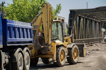 Backhoe Loader and Blue Truck on a Construction Site During Bridge Renovation
