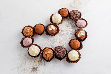 Homemade chocolate truffles with dark chocolate ganache covered with pink powder, waffle crumbles, gold flakes, coconut and nuts