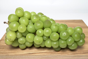 Natural, ripe grapes with large green berries on a wooden board, side view.