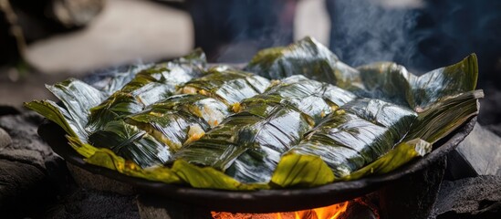 Patarashca traditional dish with ingredients wrapped in bijao leaves cooking over coals in a rustic outdoor setting