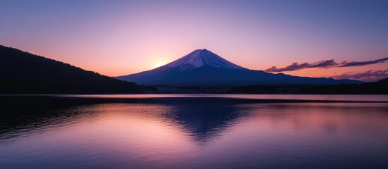 Majestic sunset over a tranquil lake reflecting the silhouette of a mountain during twilight hours