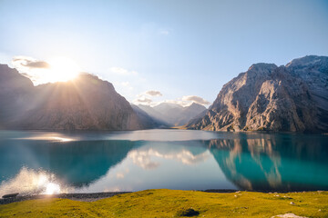 The front view of Tientang Hu lake, Xinjiang, China. There are many layers of mountains in the background. The sun was rising with yellow light reflected on the water. The idea for Trekking wallpaper.