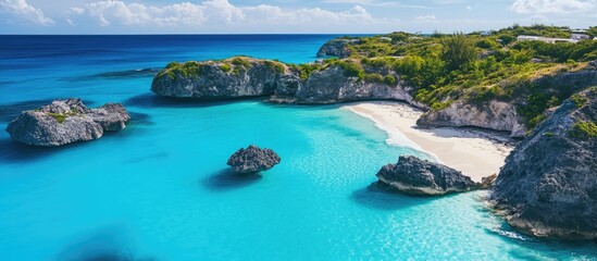 Aerial view of a picturesque rocky beach surrounded by vibrant turquoise waters and lush greenery under a bright blue sky.