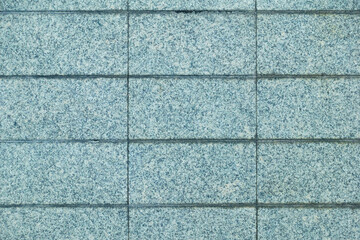 Textured blue granite wall with rectangular tiles, showcasing cool and modern aesthetic. Ideal for backgrounds or architectural designs