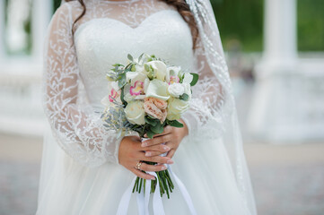 Elegant Bride Holding a Beautiful Floral Bouquet in White Wedding Dress
