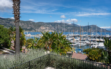 Saint-Jean-Cap-Ferrat, France - May 03, 2024: Luxury Marina with Palm Gardens and Mountain Backdrop at Mediterranean Coast
