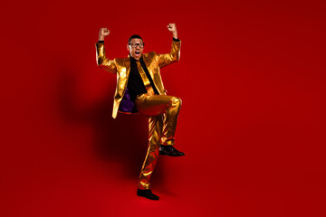 Charismatic young man in a golden suit exuding confidence on a vibrant red background
