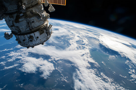 satellite is in the sky above the Earth. The satellite is in the middle of the sky and is surrounded by clouds