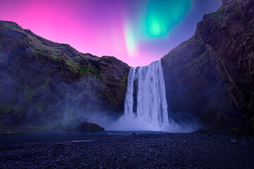 Aurora Borealis over famous Skogafoss waterfall on Skoga river, Iceland. Gorgeous Icelandic landscape with waterfall and Northern lights. Polar lights