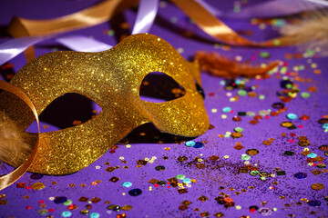 Beautiful carnival mask, ribbons and confetti on purple background, closeup