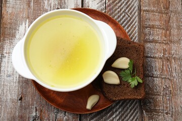 Tasty chicken bouillon served on wooden table, top view