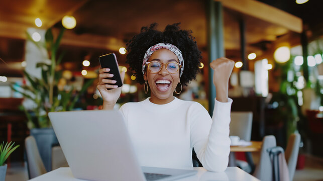 A happy woman balancing her phone and laptop work in a stylish workspace, showcasing confidence and productivity. Great for articles on team management, career development, and off