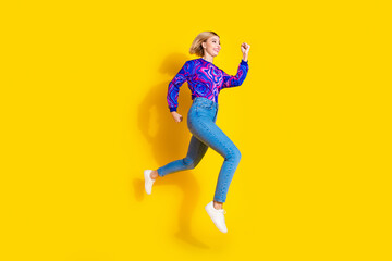 Fototapeta na wymiar Full body photo of attractive young woman running jump hurry dressed stylish colorful blue clothes isolated on yellow color background