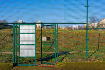 Open gate in the high fence of the children's playground, football ground.