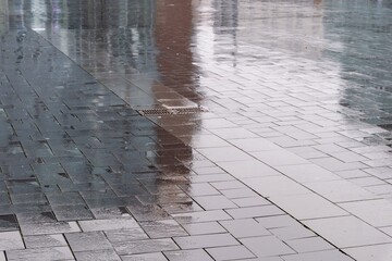 Wet pavement reflecting buildings on a rainy day
