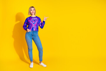 Full body photo of attractive young woman point empty space dressed stylish colorful blue clothes isolated on yellow color background