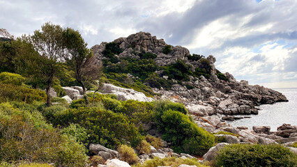 Rocky green hills and dramatic cloudy sky by the sea, wild untouched coastal landscape