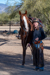 An elderly woman walking her horse in an Arizona ranch