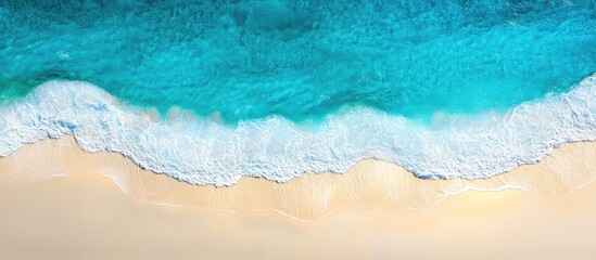Fototapeta premium Aerial view of tranquil blue ocean waves gently meeting sandy beach with ample space for creative text placement and design elements
