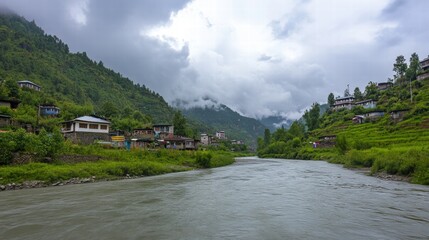 Fototapeta premium Serene River Valley: Houses nestled in lush greenery alongside a calm river, mountains and clouds in the background. A picturesque scene of tranquility and natural beauty.