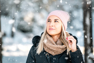Portrait of beautiful smiled woman outdoors in snowed forest copy space. Good looking woman wearing...