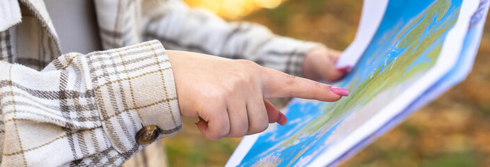A girl tourist with a map in her hand, orienting herself in the area
