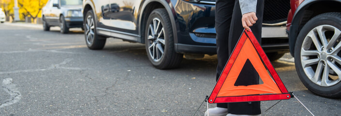 Car accident, the woman puts the warning  sign on the ground.