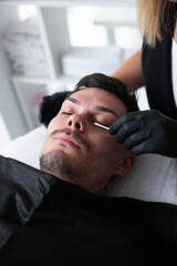 A man in a beauty salon takes care of his eyelashes