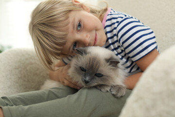 Little girl with cute kitten at home