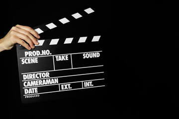 Woman with clapperboard on black background, closeup. Space for text